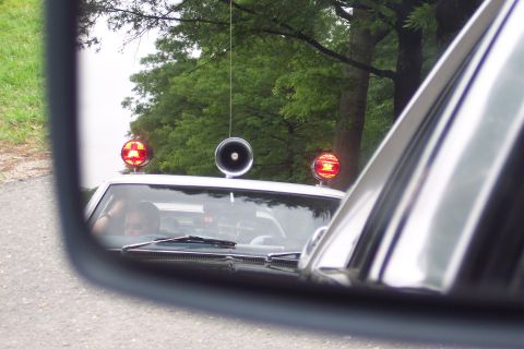 2001 Ford Crown Victoria - A white police car with red emergency lights and a siren is reflected in a side mirror.
