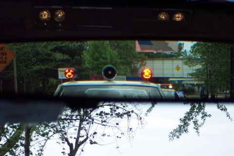2001 Ford Crown Victoria - View from inside a police car shows flashing lights and a siren on the roof.
