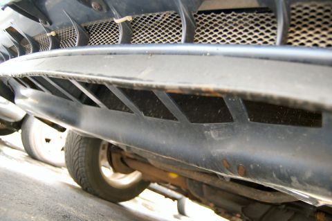 1985 Mercury Grand Marquis - Close-up view of a car's undercarriage, revealing the front bumper and a wheel.