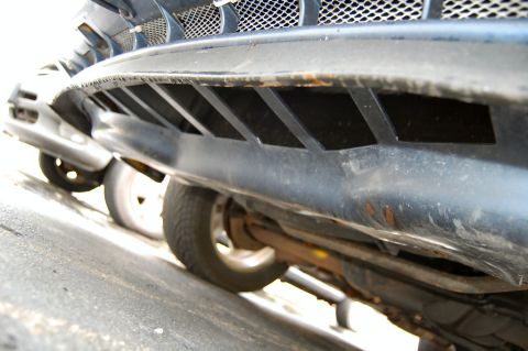 1985 Mercury Grand Marquis - The underside of a car's front end is visible, with a dark grille and air dam horizontal openings.