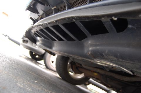 1985 Mercury Grand Marquis - The underside of a car's bumper, showing ventilation slots and parts of the wheels and exhaust system.