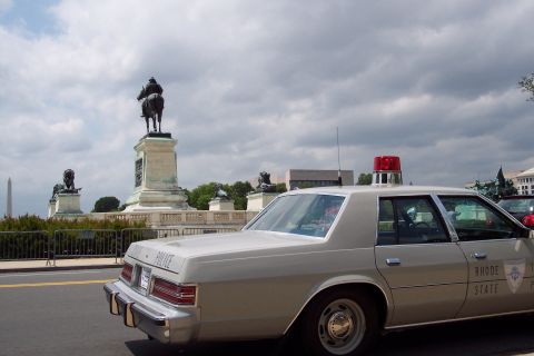2001 Ford Crown Victoria - A Rhode Island State Police car is parked near a monument with a statue on horseback.