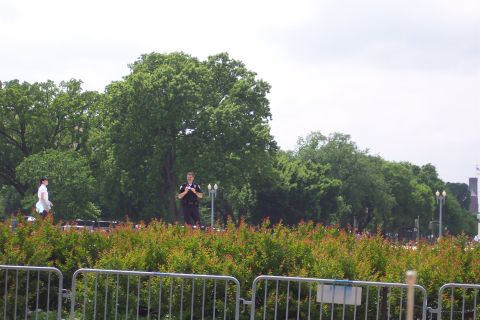 2001 Ford Crown Victoria - A police officer stands guard in a park-like setting with trees and manicured bushes.