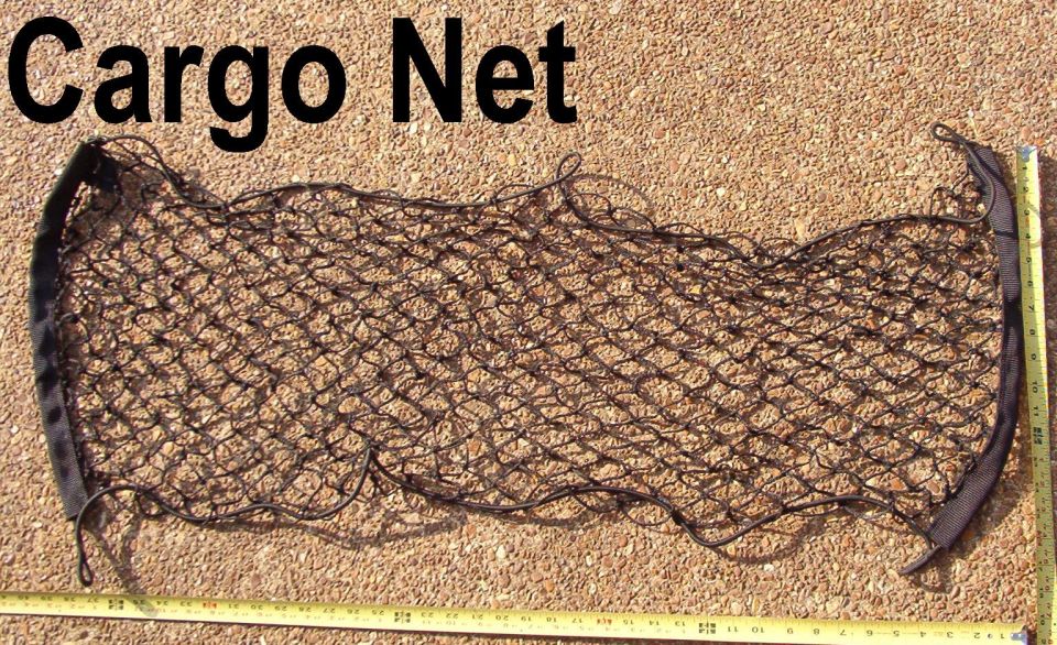 Black mesh cargo net laid flat on gravel next to a tape measure