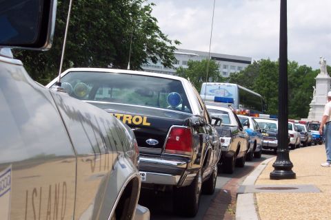 2001 Ford Crown Victoria - A line of police vehicles, including a 2001 Ford Crown Victoria, are parked on a street.