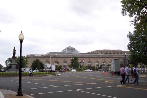 2001 Ford Crown Victoria - A street scene in Washington DC shows a large building with a glass dome, multiple vehicles, and pedestrians.
