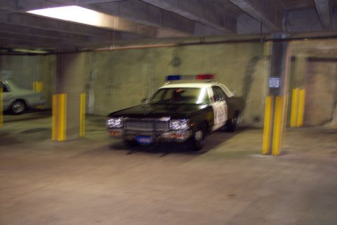 2001 Ford Crown Victoria - A vintage police car with a light bar is parked in a concrete garage, dimly lit garage.
