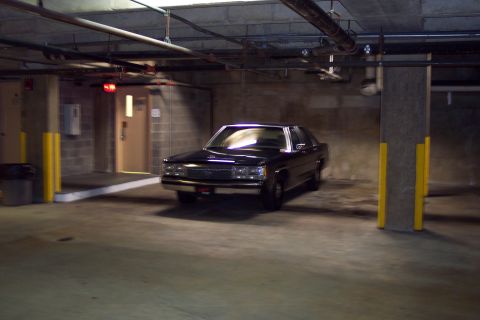 2001 Ford Crown Victoria - A black sedan is parked in a concrete garage with yellow safety posts and overhead pipes.