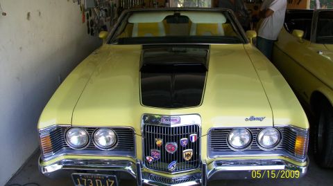 1973 Mercury Cougar - Front view of a yellow 1973 Mercury Cougar convertible, showing its grille with multiple emblems and a black hood scoop.