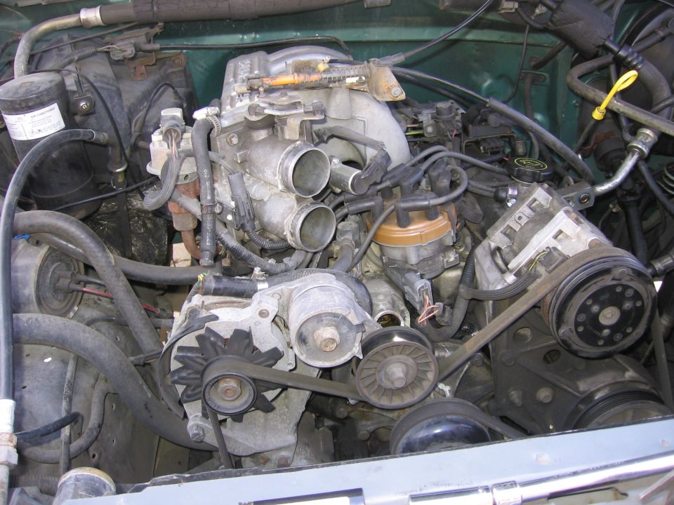 Engine bay with V8 engine, distributor, alternator, and AC compressor visible