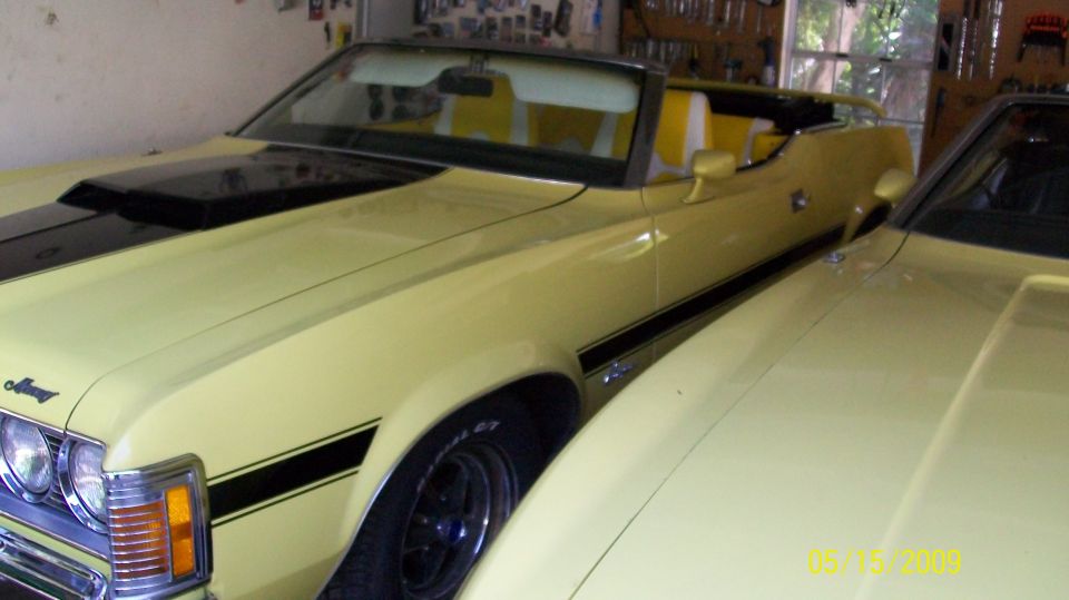 Yellow convertible with top down and white interior parked in a garage