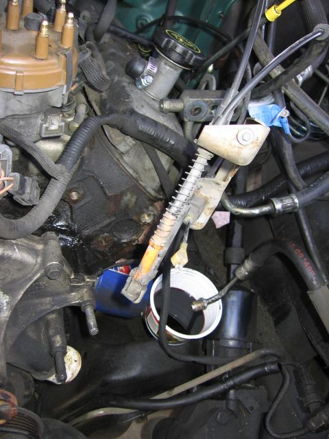 1990 Ford Bronco - Close-up view of an engine bay, focusing on an oil filter and a cup collecting fluid.