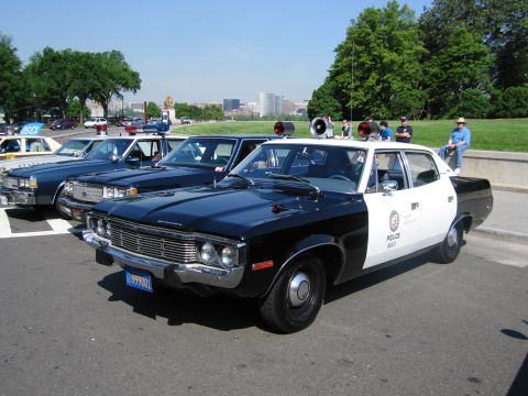 1991 Ford LTD Crown Victoria - black-and-white AMC police sedan lettered POLICE with a brush guard is parked on pavement, with onlookers and other cruisers nearby.