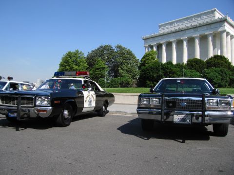 1991 Ford LTD Crown Victoria - black-and-white highway patrol cruiser and a dark Dodge sedan are parked on pavement in front of the columned Lincoln Memorial.