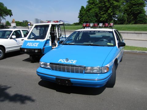 1991 Ford LTD Crown Victoria - Front view of a blue and white NYPD police sedan with roof light bar and In Memory of 23 Shields lettering on the windshield.