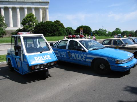 1991 Ford LTD Crown Victoria - small blue NYPD three-wheeled police scooter parked next to a blue NYPD Chevrolet patrol sedan near the Lincoln Memorial.
