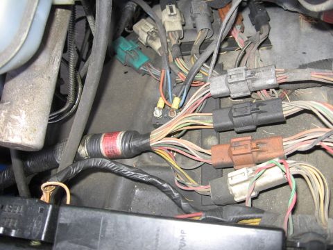 1990 Ford Bronco - Close-up of a vehicle's engine wiring harness, showing various connectors and bundled wires.