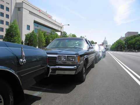 1991 Ford LTD Crown Victoria - Front quarter view of a dark vintage sedan parked curbside along a city street, with the US Capitol dome in the distance.