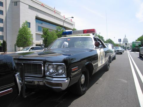 1991 Ford LTD Crown Victoria - black-and-white police sedan bearing a CHP-style star and roof light bar parked along a street with the US Capitol behind.