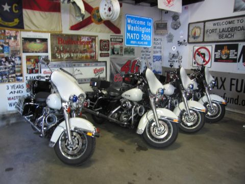 1991 Ford LTD Crown Victoria - White police motorcycles are lined up inside a garage with state flags and a Welcome to Washington NATO 50th sign on the wall.