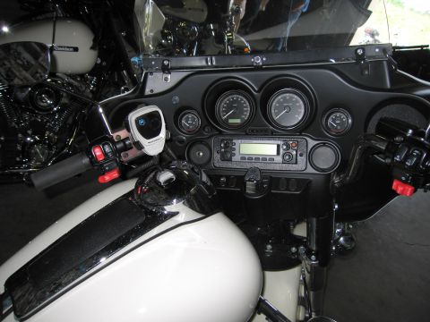1991 Ford LTD Crown Victoria - close-up of a white police motorcycle's fairing showing twin gauges, a two-way radio, switch controls, and a mounted BMW navigation unit.