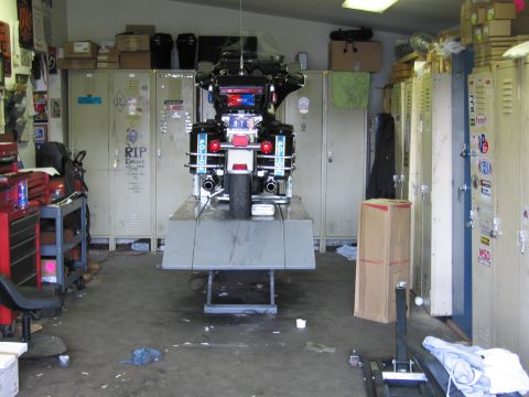 1991 Ford LTD Crown Victoria - Rear view of a police touring motorcycle with red emergency lighting, lifted in a garage lined with lockers and a tool chest.