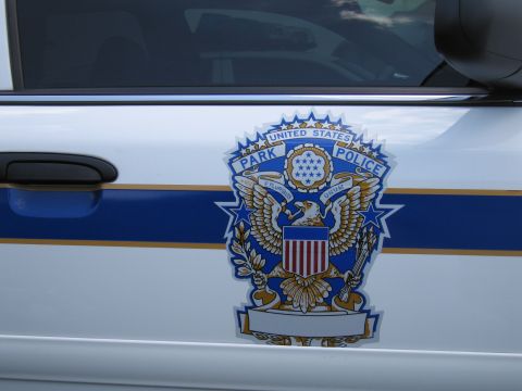 1991 Ford LTD Crown Victoria - Close-up of a United States Park Police eagle-and-shield crest decal on the white door of a police car with blue and gold stripes.