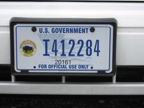 1991 Ford LTD Crown Victoria - blue-on-white U.S. Government license plate reading I412284 and FOR OFFICIAL USE ONLY mounted on a white vehicle bumper.