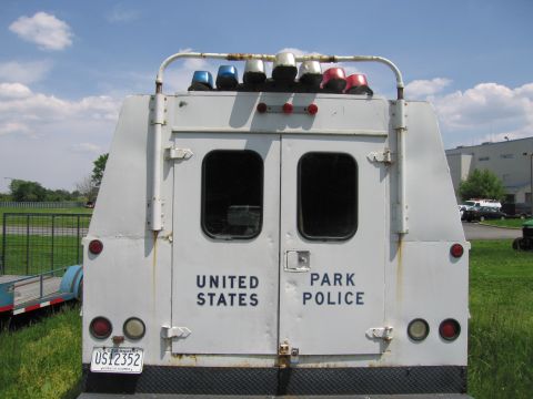 1991 Ford LTD Crown Victoria - straight-on rear of a white United States Park Police box truck shows twin doors with windows, a roof light rack and a US Government plate.