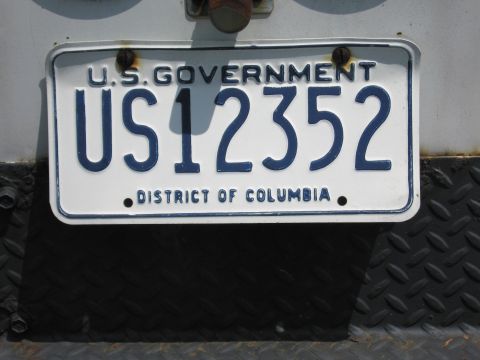 1991 Ford LTD Crown Victoria - close-up of a white U.S. Government District of Columbia license plate reading US12352, bolted to a diamond-plate metal panel.
