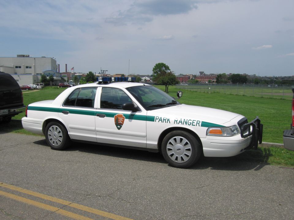 White and green Park Ranger Ford Crown Victoria cruiser with NPS arrowhead emblem parked on grass