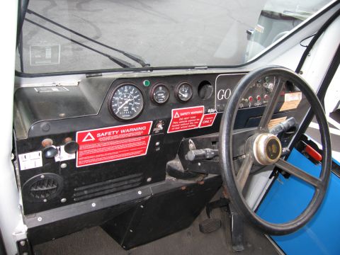 1991 Ford LTD Crown Victoria - interior dashboard of a small three-wheeled vehicle shows round gauges, a black steering wheel and red SAFETY WARNING decals.