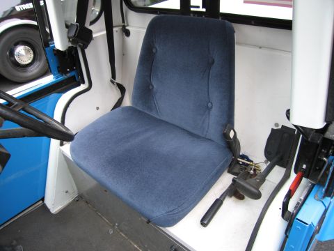1991 Ford LTD Crown Victoria - single blue cloth bucket seat sits inside a small white vehicle cab with exposed blue framework and a steering wheel to the left.
