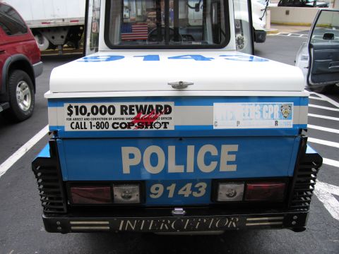 1991 Ford LTD Crown Victoria - Rear close-up of an NYPD police scooter showing POLICE 9143 and a $10,000 reward Cop Shot decal above the bumper.
