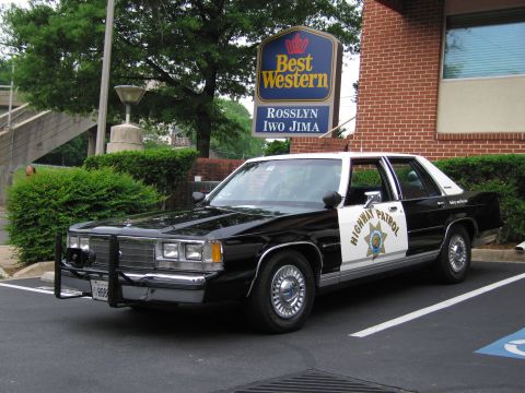 1991 Ford LTD Crown Victoria - black and white Ford Highway Patrol sedan with a push bumper parked under a Best Western Rosslyn Iwo Jima sign.