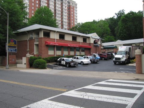 1991 Ford LTD Crown Victoria - Wide street view of a Best Western parking lot holding several marked police cars and a delivery box truck.