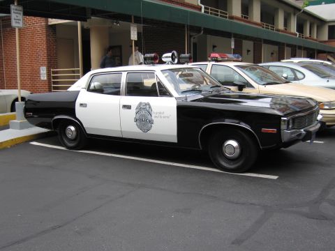 1991 Ford LTD Crown Victoria - black and white AMC police sedan with a door badge reading POLICE and to protect and to serve parked at a motel.