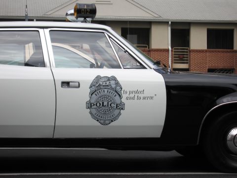 1991 Ford LTD Crown Victoria - Close-up of a black and white police car door showing a North Haven Connecticut Police badge and to protect and to serve motto.