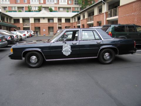 1991 Ford LTD Crown Victoria - dark blue Ford LTD Crown Victoria police cruiser with a North Haven Police door emblem parked in a lot beside brick buildings.