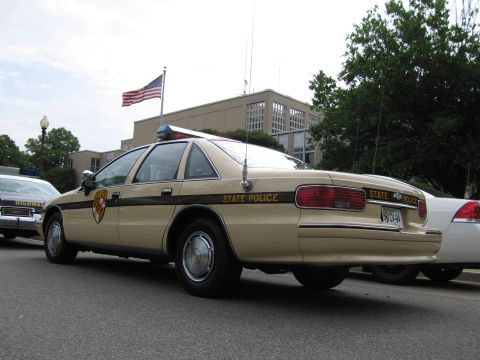 1991 Ford LTD Crown Victoria - Rear three-quarter view of a tan-and-brown Chevrolet Caprice State Police cruiser parked in a row of police cars.