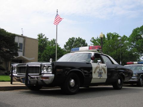 1991 Ford LTD Crown Victoria - Front three-quarter view of a black-and-white Highway Patrol sedan with push bumper and roof light bar in a parking area.