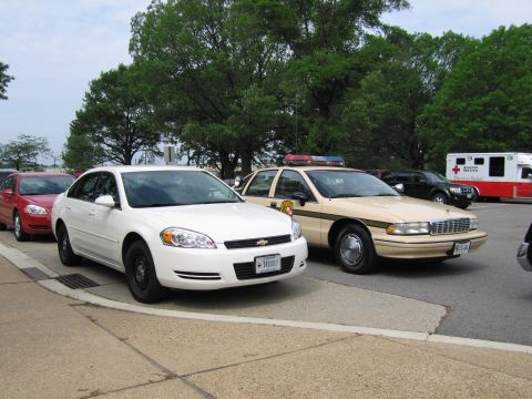 1991 Ford LTD Crown Victoria - white Chevrolet Impala sedan parked beside a tan-and-white Chevrolet Caprice, with an American Red Cross vehicle in the background.