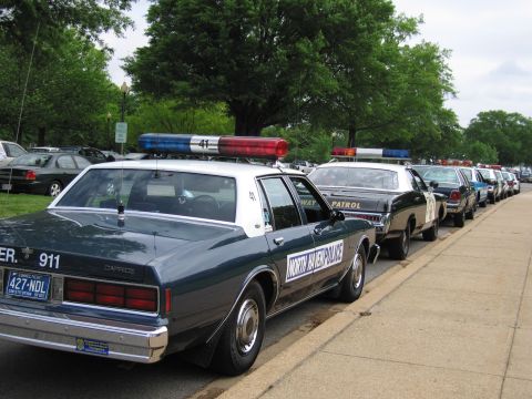 1991 Ford LTD Crown Victoria - Rear view of a Chevrolet Caprice police car marked North Haven Police, with roof lightbar, leading a line of cruisers at the curb.