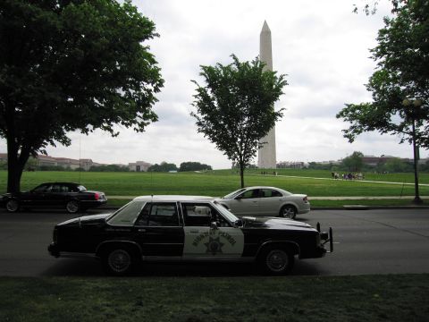 1991 Ford LTD Crown Victoria - black-and-white Highway Patrol cruiser with a gold star door emblem parked near the Washington Monument.
