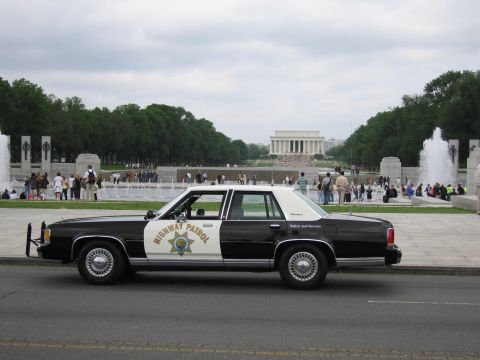 1991 Ford LTD Crown Victoria - black-and-white Highway Patrol Ford cruiser parked in front of the Lincoln Memorial and fountains at the National Mall.