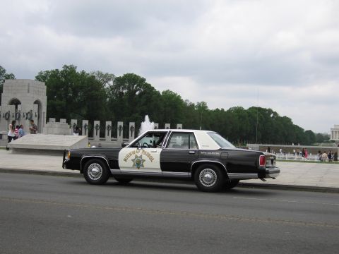 1991 Ford LTD Crown Victoria - Side view of a black-and-white Highway Patrol cruiser at the World War II Memorial, the Lincoln Memorial in the distance.
