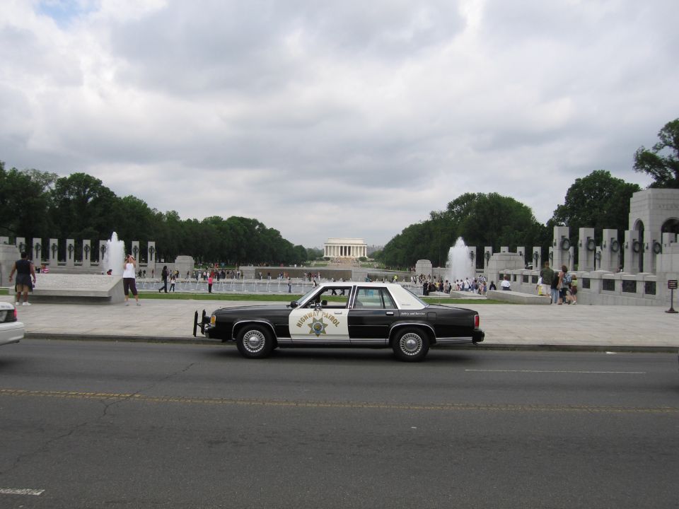 Black-and-white Highway Patrol sedan parked across from the Lincoln Memorial reflecting area
