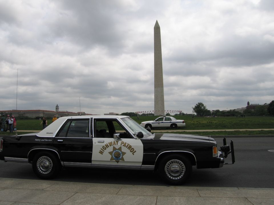Side view of a black-and-white Highway Patrol sedan with the Washington Monument behind