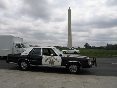 1991 Ford LTD Crown Victoria - black-and-white Highway Patrol cruiser parked before the Washington Monument, a white police car and box truck nearby.
