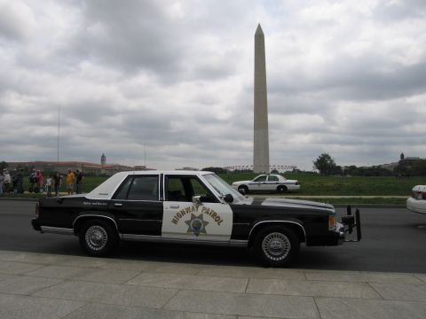 1991 Ford LTD Crown Victoria - black-and-white Highway Patrol cruiser parked along a curb with the Washington Monument behind it.